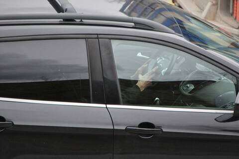 Photo of driver holding their phone while driving
