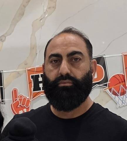 Man with dark hair and long beard. Wearing a black shirt.