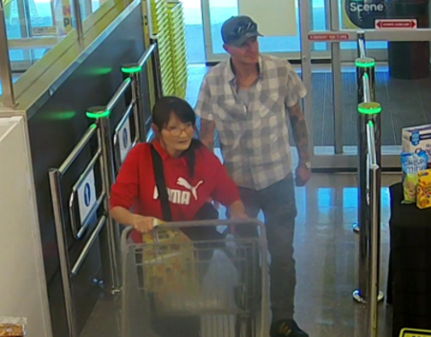 Image of a woman pushing a shopping cart and a man walking behind her.