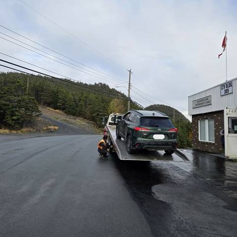 a green sport utility vehicle is loaded onto the bed of a tow truck