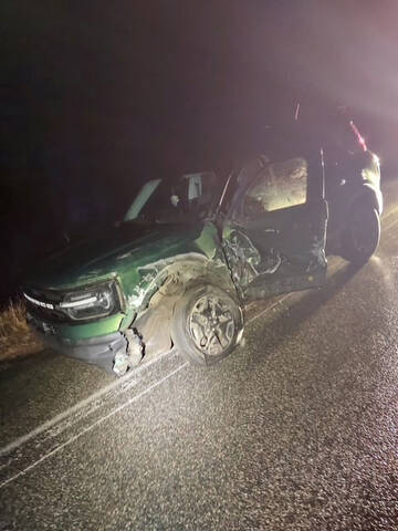 A green Ford Bronco with significant damage down the driver’s side of the vehicle.