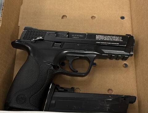 Seized black air soft handgun in a cardboard box, with the magazine visible separately.