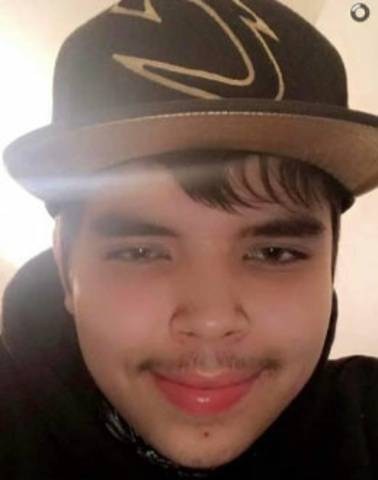 Teenage boy with black hair, brown eyes, a subtle moustache. He is wearing a black hoodie and a black ball cap.