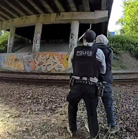 Photo of officer arresting shoplifting suspect near some train tracks