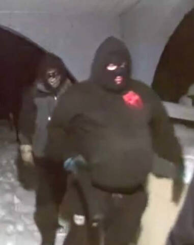 Person wearing all black clothing, including a black face covering. // Personne vêtue entièrement de noir, y compris d'un masque noir.
