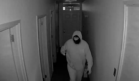Black and white photo of a male wearing a face covering in a building. // Photo en noir et blanc d'un homme portant un masque dans un bâtiment.