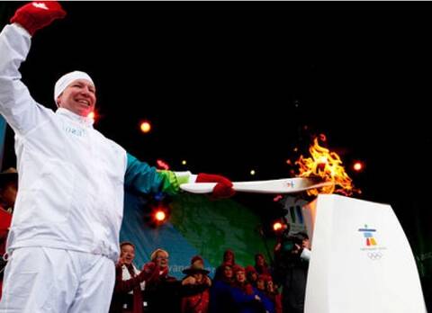 Dave Jephson stands on podium with Olympic torch