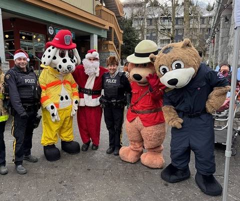 A photo of two Royal Canadian Mounted Police officers with Santa Claus, Sparky, Safety Bear and Bearamedic