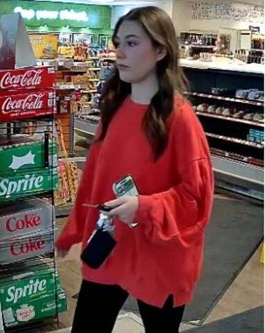 Surveillance image of a woman in a red sweater and black leggings sought in relation to a gas station theft in Whitbourne, Newfoundland and Labrador