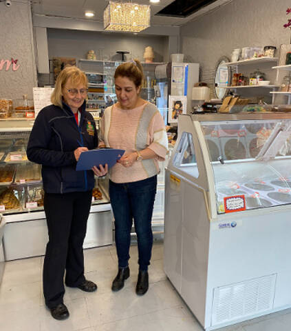 Two women looking at a clipboard in a business setting