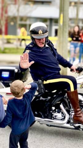 RCMP member on a motorcycle high-fiving a child