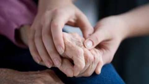 Stock photo of a person holding the hand of an elderly person.