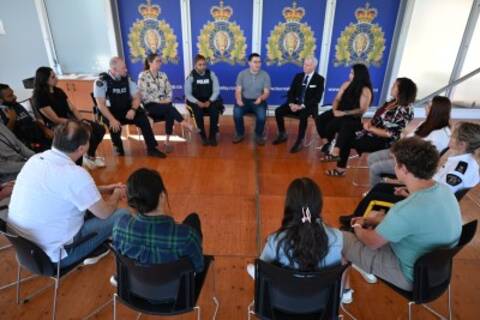 A group of people sit in a circle indoors on chairs in a circle