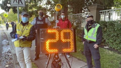 Speed Watch volunteers standing next to a radar speed sign