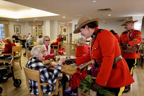 RCMP officer handing out roses during a Valentines day community event at a local seniors home