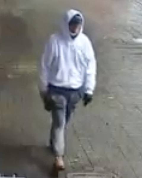 Photo of suspect wearing white hoodie, baseball cap, grey track pants, and brown shoes