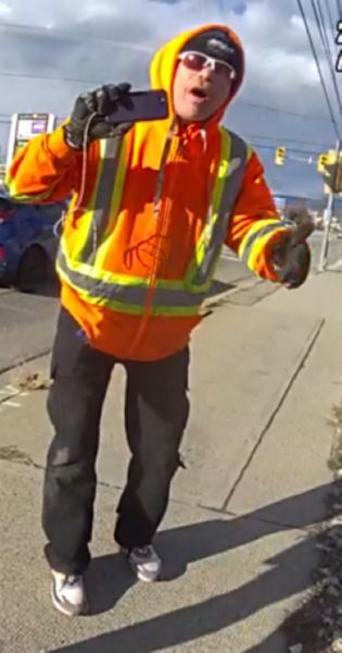 Man in high visibility vest and sunglasses filming with his cellphone